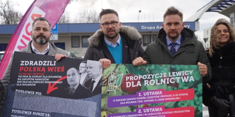 Grupa ludzi stojąca na zewnątrz w Puławach trzyma baner z hasłem „Aby nigdy więcej rolnik nie musiał sprzedawać poniżej kosztów produkcji”, wyrażając obronę polskiej wsi.