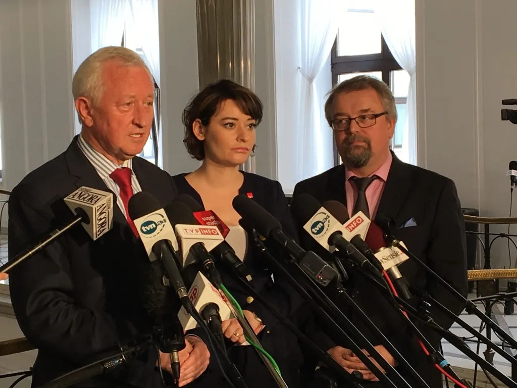 Trzy osoby stoją przed wieloma mikrofonami podczas konferencji prasowej o prawach socjalnych w Europie.