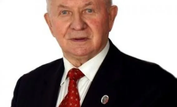 Starszy mężczyzna w garniturze i czerwonym krawacie na białym tle, ilustrujący wypowiedź eksperta oceniającego Donalda Trumpa.