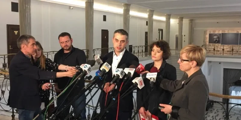 Grupa osób udziela oświadczenia prasowego stojąc przed wieloma mikrofonami w reprezentacyjnym holu; kontekst: deklaracja ONR.