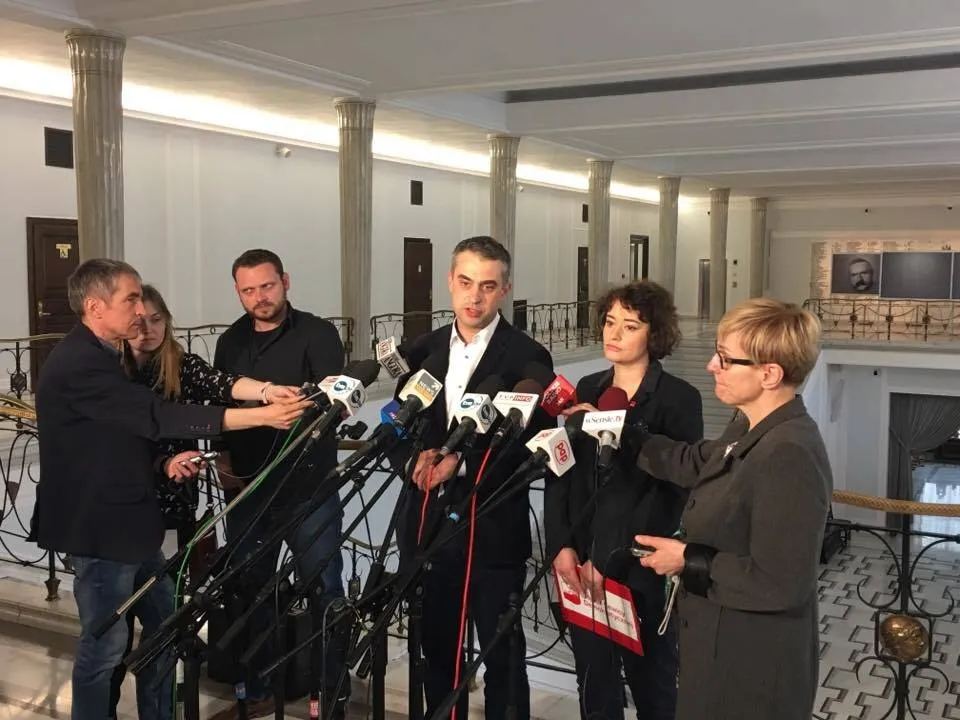 Grupa osób udziela oświadczenia prasowego stojąc przed wieloma mikrofonami w reprezentacyjnym holu; kontekst: deklaracja ONR.