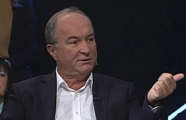 Mężczyzna w marynarce i białej koszuli gestykuluje podczas dyskusji w studiu telewizyjnym o służbach mundurowych.