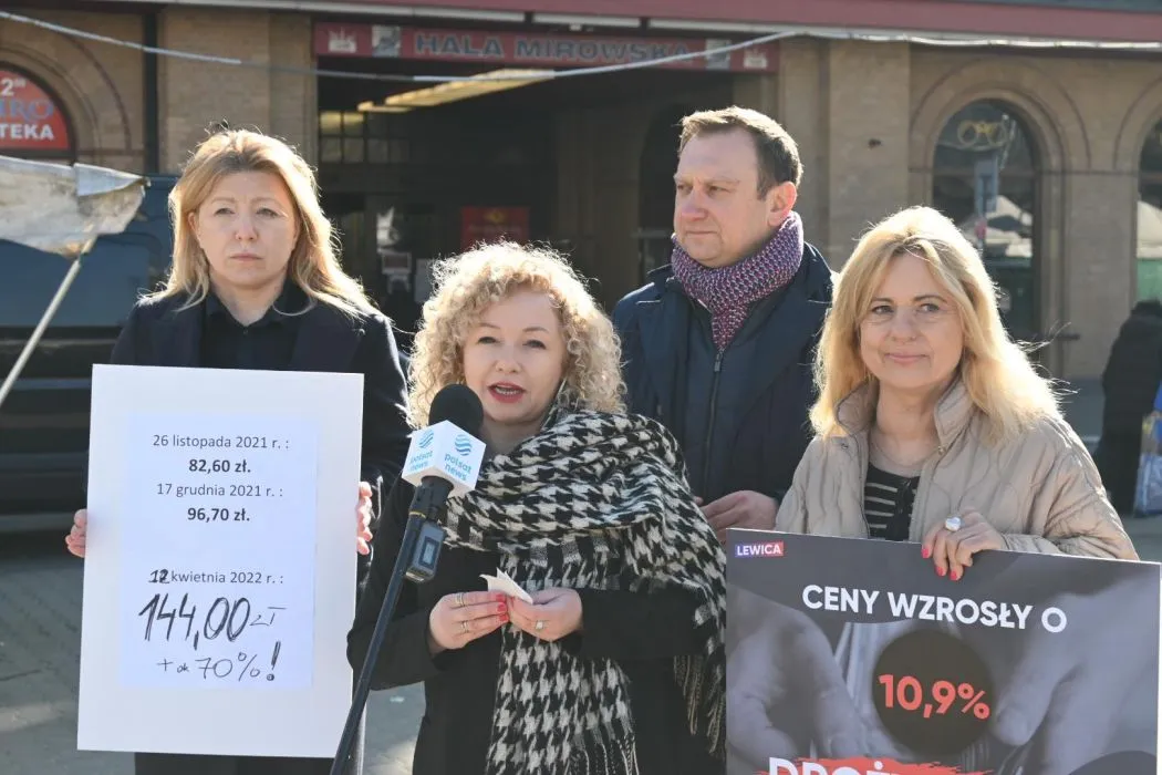 Grupa czterech osób Lewicy stoi na ulicy podczas konferencji prasowej; jedna kobieta mówi do mikrofonu, dwie trzymają plakaty ilustrujące wzrost cen żywności.