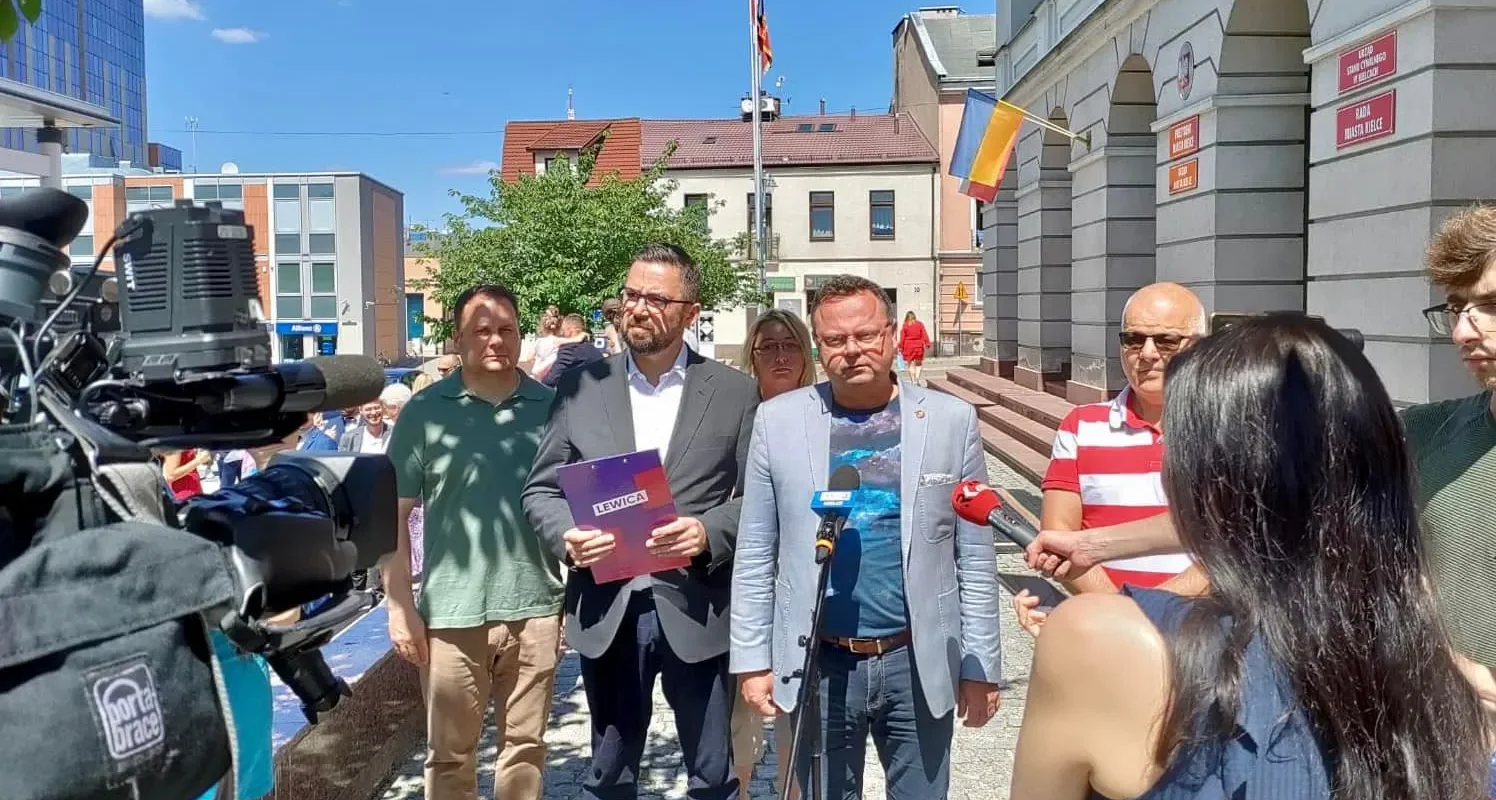 Grupa osób udziela konferencji prasowej przed urzędem miasta Pacanów, a dziennikarze z kamerą i mikrofonami relacjonują wydarzenie.