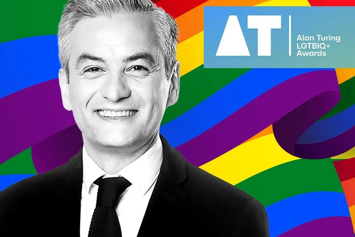 Portret mężczyzny w garniturze na tle tęczowej grafiki z logo Alan Turing LGBTQ+ Awards.