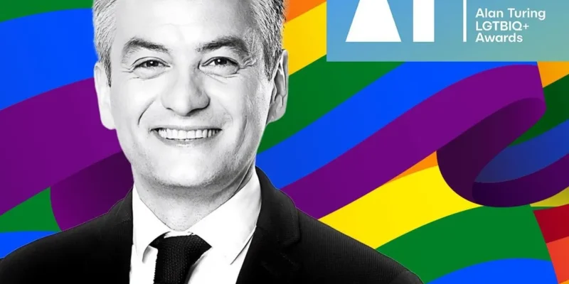 Portret mężczyzny w garniturze na tle tęczowej grafiki z logo Alan Turing LGBTQ+ Awards.