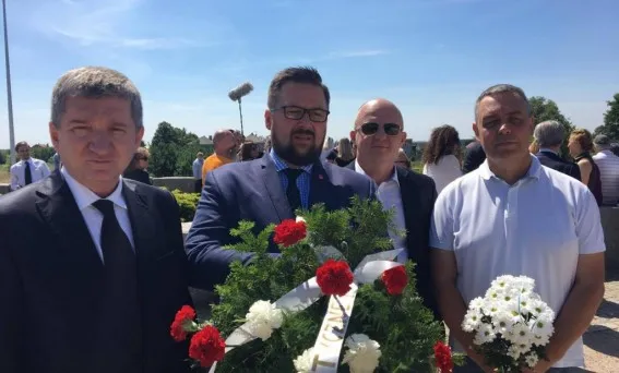 Czterech mężczyzn trzyma wieńce i bukiet kwiatów podczas uroczystości pamięci zamordowanych Żydów w Jedwabnem.