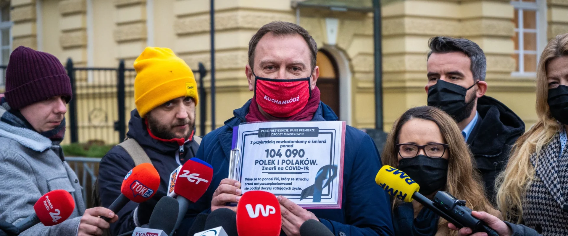 Grupa Lewicy wychodzi ze spotkania u premiera, domagając się konkretnego planu działań i harmonogramu, trzymając kartę z liczbą ofiar COVID-19 przy mikrofonach mediów.