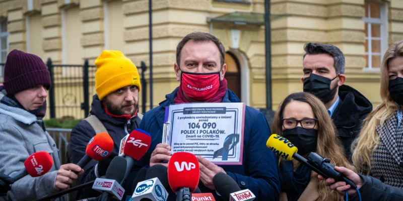 Grupa Lewicy wychodzi ze spotkania u premiera, domagając się konkretnego planu działań i harmonogramu, trzymając kartę z liczbą ofiar COVID-19 przy mikrofonach mediów.