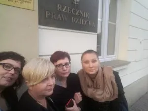 Na zdjęciu (zgodnie z opisem) cztery kobiety stoją razem przed wejściem do budynku z tablicą "Rzecznik Praw Dziecka".