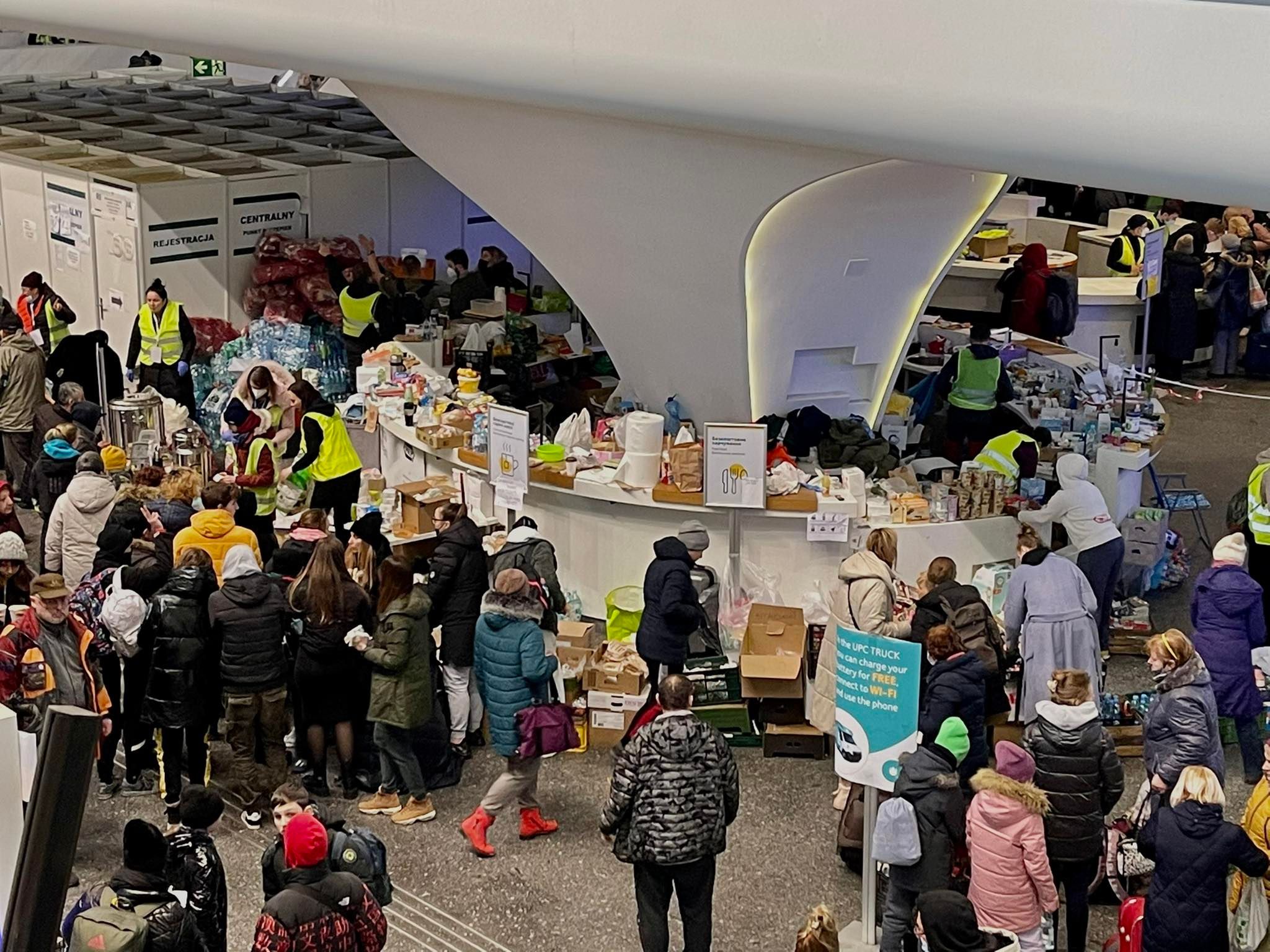 Zatłoczony warszawski dworzec, na którym wolontariusze w żółtych kamizelkach organizują zbiórkę i rozdział darów dla osób potrzebujących.