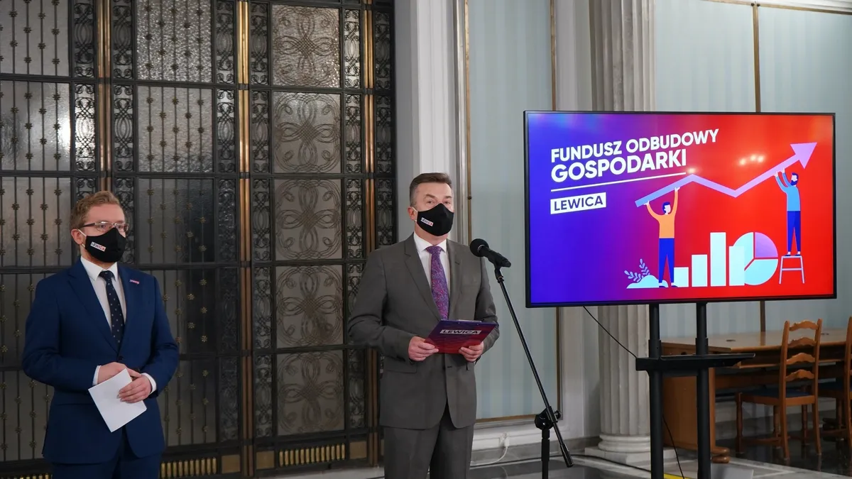 Dwóch mężczyzn w garniturach i maseczkach stoi przy mikrofonie podczas prezentacji o Funduszu Odbudowy Gospodarki; na ekranie w tle widać napis „Fundusz Odbudowy Gospodarki” i rosnący wykres.