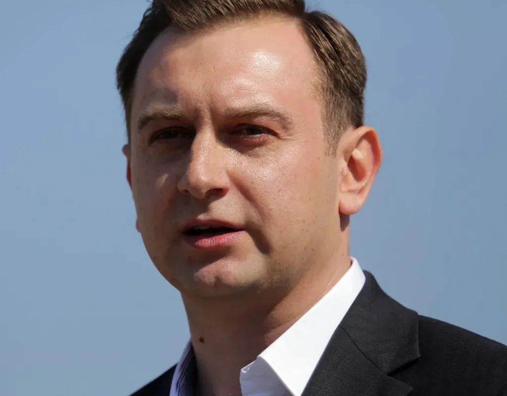 Zbliżenie mężczyzny w garniturze przemawiającego na tle nieba, ilustrujące efekty miejskiego programu, dzięki któremu osoby bezdomne znajdują pracę.