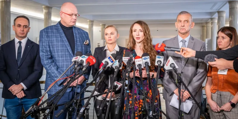 Konferencja prasowa z udziałem kilku osób stojących przed mikrofonami, podczas której jedna z uczestniczek wygłasza oświadczenie.