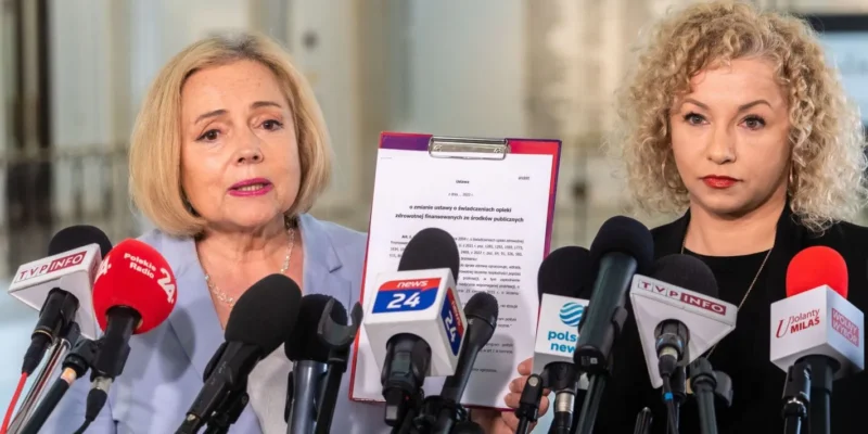 Konferencja prasowa, na której jedna z mówczyń prezentuje dokument dotyczący zmian w ustawie o świadczeniach opieki zdrowotnej.