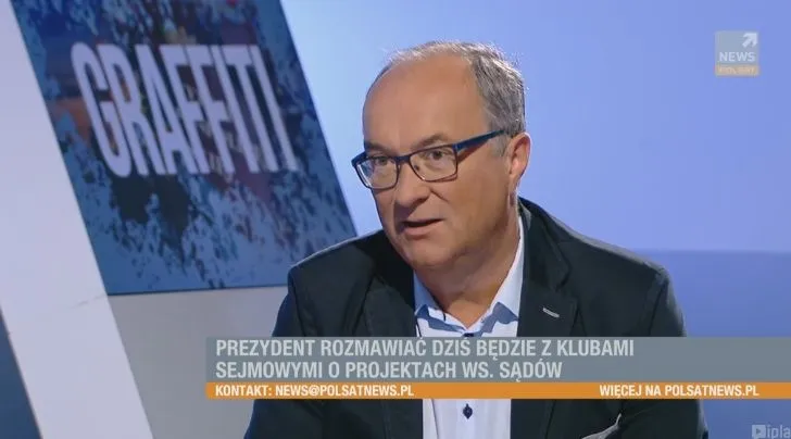 Mężczyzna w okularach i marynarce mówi w studiu telewizyjnym, na dolnym pasku widoczny napis o rozmowach prezydenta z klubami sejmowymi ws. projektów dotyczących sądów.