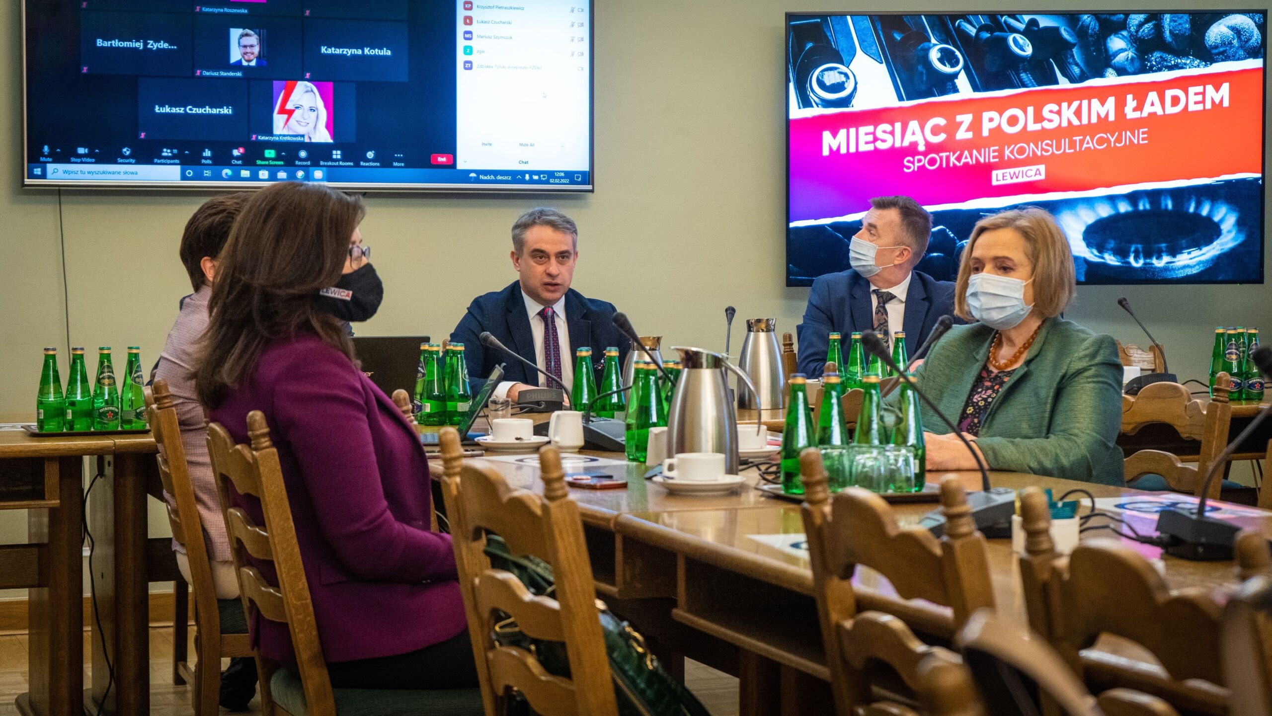 Spotkanie konsultacyjne „Miesiąc z Polskim Ładem” z udziałem uczestników zarówno na sali, jak i zdalnie, odbywające się w przestrzeni z zielonymi butelkami wody.