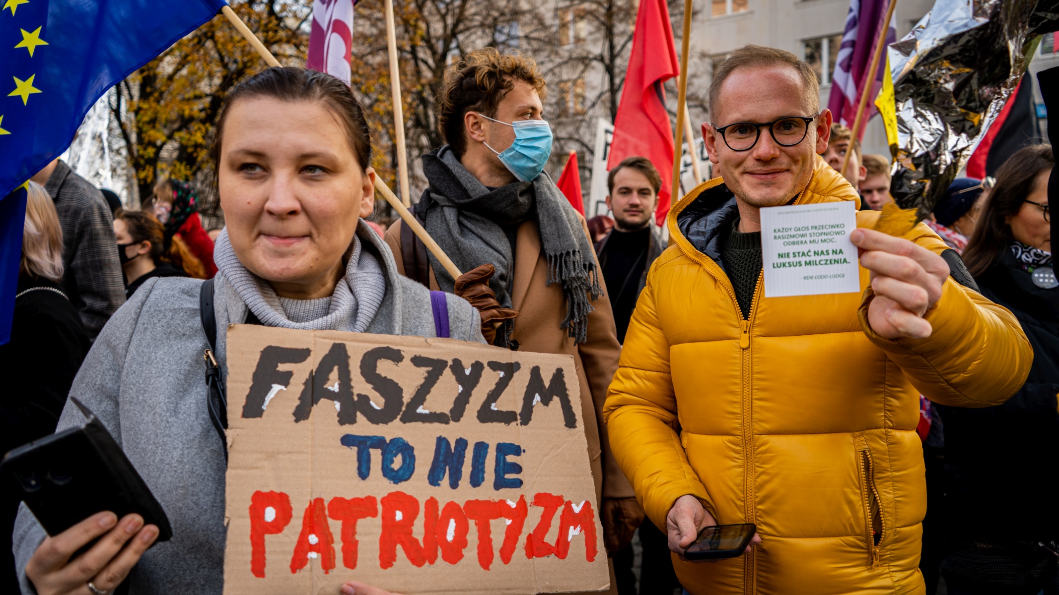 Na zdjęciu uczestnicy protestu trzymają transparenty i flagi, wyrażając sprzeciw wobec faszyzmu i nietolerancji.
